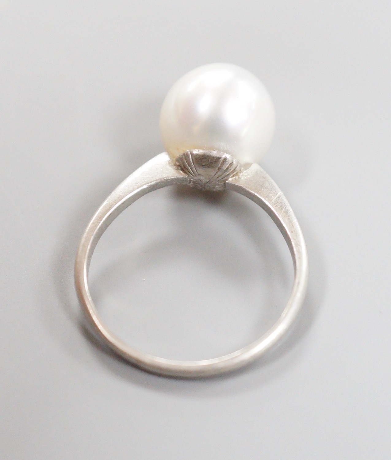 A white metal (stamped Plat) and single stone cultured pearl ring, size O, gross weight 4.1 grams.